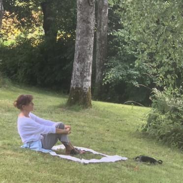 Frau im wERDschätzungsrahmen auf einer leicht abfallenden Wiese sitzend