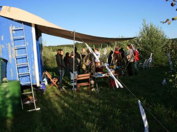 Ankommen bei abendlichem Sonnenschein in unserem Gemeinschaftsgarten: Eine fröhliche Runde von Teilnehmenden trifft sich am Buffet, bevor das Konzert beginnt. Foto: Rudolf H. Ende