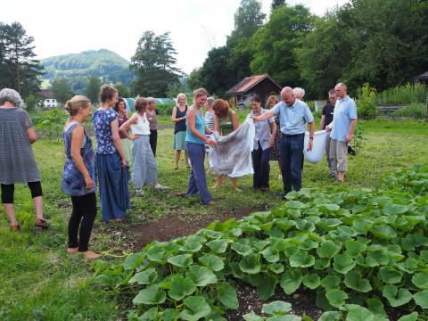 Eine Gruppe sommerlich gekleideter Menschen vollführt ein Lebendigleitsritual